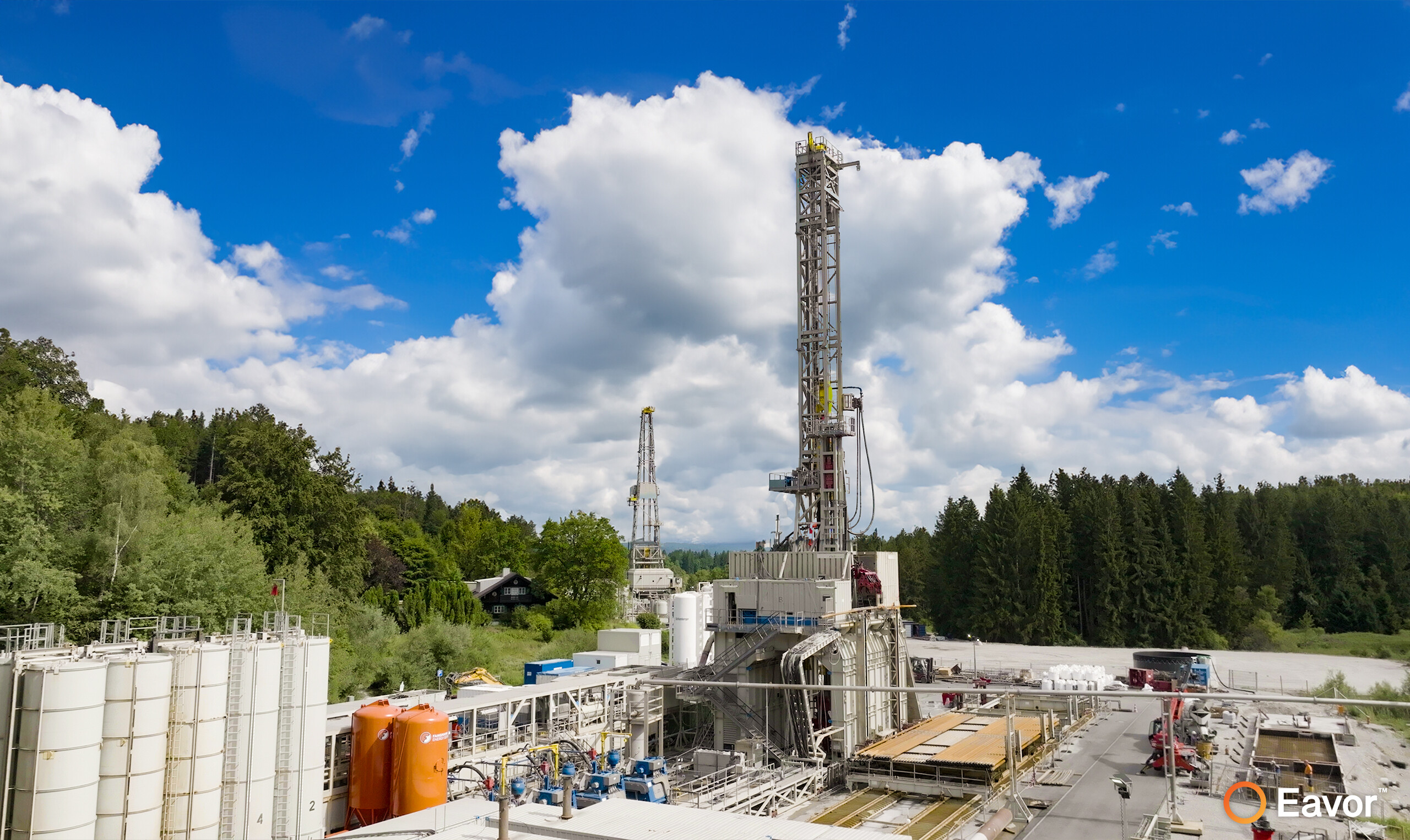 Eavor-Europe™ - Eavor's first commercial geothermal plant with a cloudy blue sky and intensely green trees in the background.