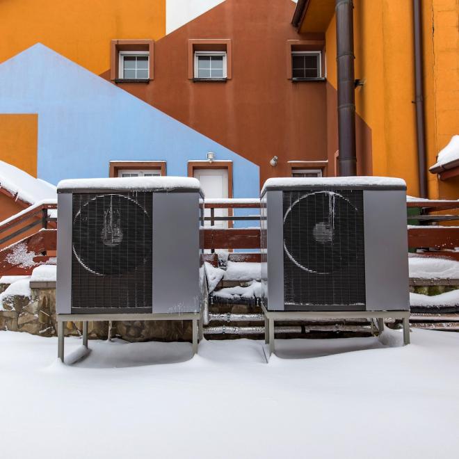 Two residential modern heat pumps buried in snow.